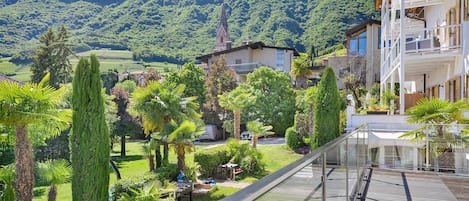 A balcony with a view of a mountainous landscape, a church, and a residential building.