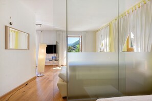 Ein modernes Hotelzimmer mit einem großen Bett, einem Fernseher, einem Schreibtisch und Blick ins Freie.
