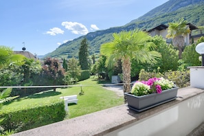 Un balcone con vista sul giardino, una panchina bianca e un'antenna parabolica.
