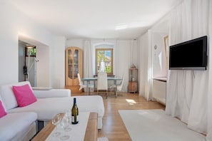 Un soggiorno moderno con un divano bianco, un tavolo da pranzo e una TV a parete.