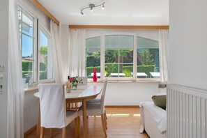 Zona pranzo con tavolo, sedie e vista sul verde.