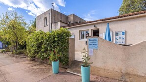 A building with a reception sign, a window, and a blue umbrella. - Family Villa Near Favone Beach (Sari-Solenzara)