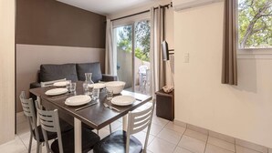 A dining area with a table set for four, a sofa, and a TV mounted on the wall. - Family Villa Near Favone Beach (Sari-Solenzara)