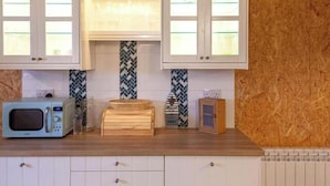 A kitchen with white cabinets, a microwave, a toaster, and a patterned backsplash. - Yurt with Private hot tub and bathroom (Marshwood Dorset)