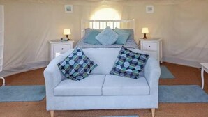 A tented room with a bed, a sofa, two bedside tables with lamps, and a view of the sky. - Yurt with Private hot tub and bathroom (Marshwood Dorset)