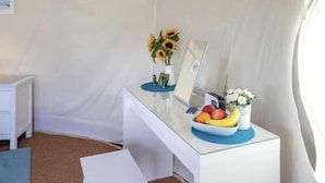 A white desk with a laptop, a vase with sunflowers, a fruit bowl, and a small potted plant. - Yurt with Private hot tub and bathroom (Marshwood Dorset)