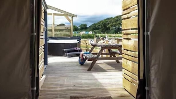 An open tent with a wooden deck, a picnic table, and a bench. - Yurt with Private hot tub and bathroom (Marshwood Dorset)