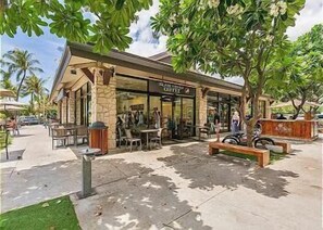Ein Restaurant mit Außenbereich, einer Steinfassade und Palmen.