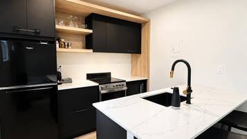 A modern kitchen with black appliances, a white marble countertop, and a black faucet.