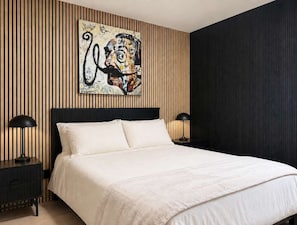Une chambre moderne avec un grand lit, deux tables de chevet et un tableau accroché au mur.