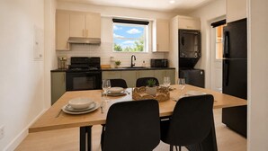 A compact kitchen with a dining table set for two, a stove, microwave, and black appliances. - Familles & Groups | 3 Bedrooms for 8 | A/C | U9 (Québec City)