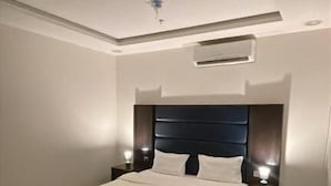 Ein Hotelzimmer mit Bett, Nachttischen, einem Schreibtisch und einer Klimaanlage.
