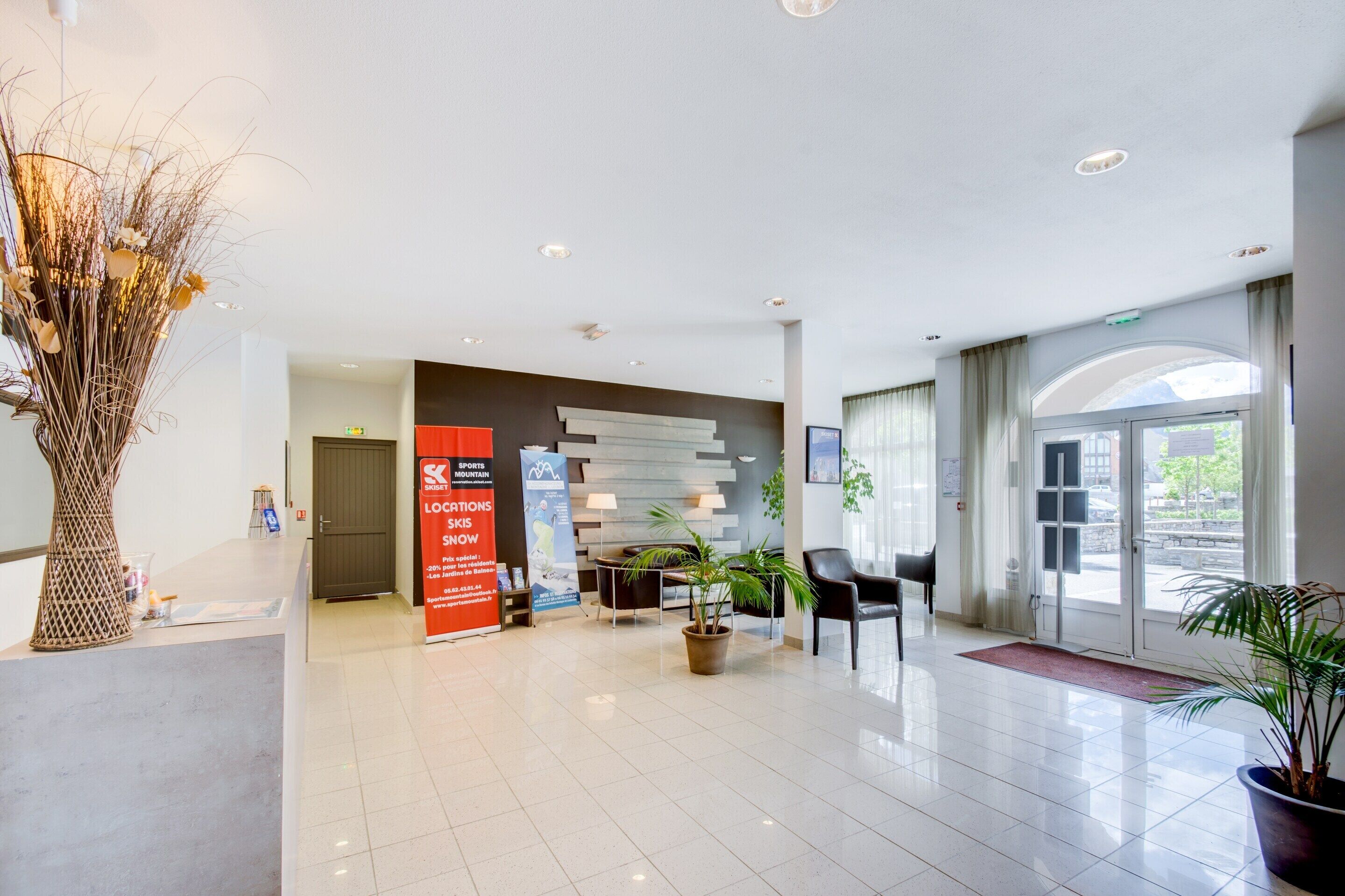 A modern lobby with a reception desk, seating area, and large windows.