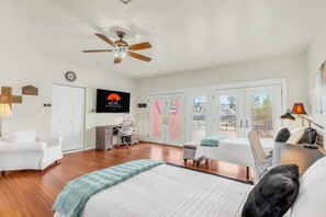A hotel room with a bed, a desk, a chair, a ceiling fan, and a view through the glass doors. - Private Hot Tub, Firepit & Duck Pond Near Canyon Lake + Whitewater Amphitheater (Canyon Lake)