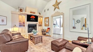 A living room with leather sofas, a fireplace, a television, and a star decoration on the wall. - Private Hot Tub, Firepit & Duck Pond Near Canyon Lake + Whitewater Amphitheater (Canyon Lake)