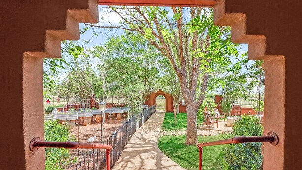 A pathway leading to an archway surrounded by greenery and outdoor seating. - Private Hot Tub, Firepit & Duck Pond Near Canyon Lake + Whitewater Amphitheater (Canyon Lake)