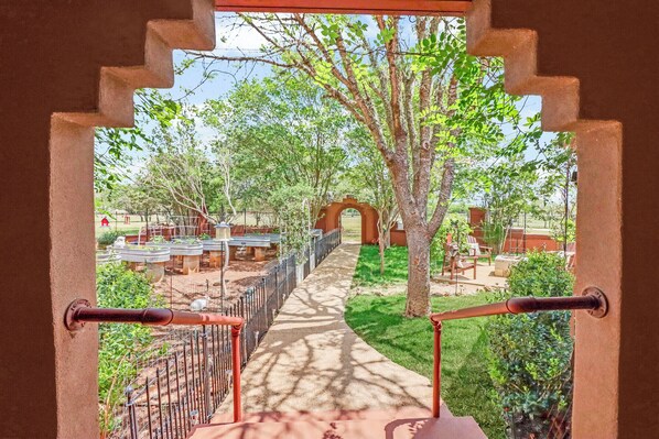 A pathway leading to an archway surrounded by greenery and outdoor seating. - Private Hot Tub, Firepit & Duck Pond Near Canyon Lake + Whitewater Amphitheater (Canyon Lake)
