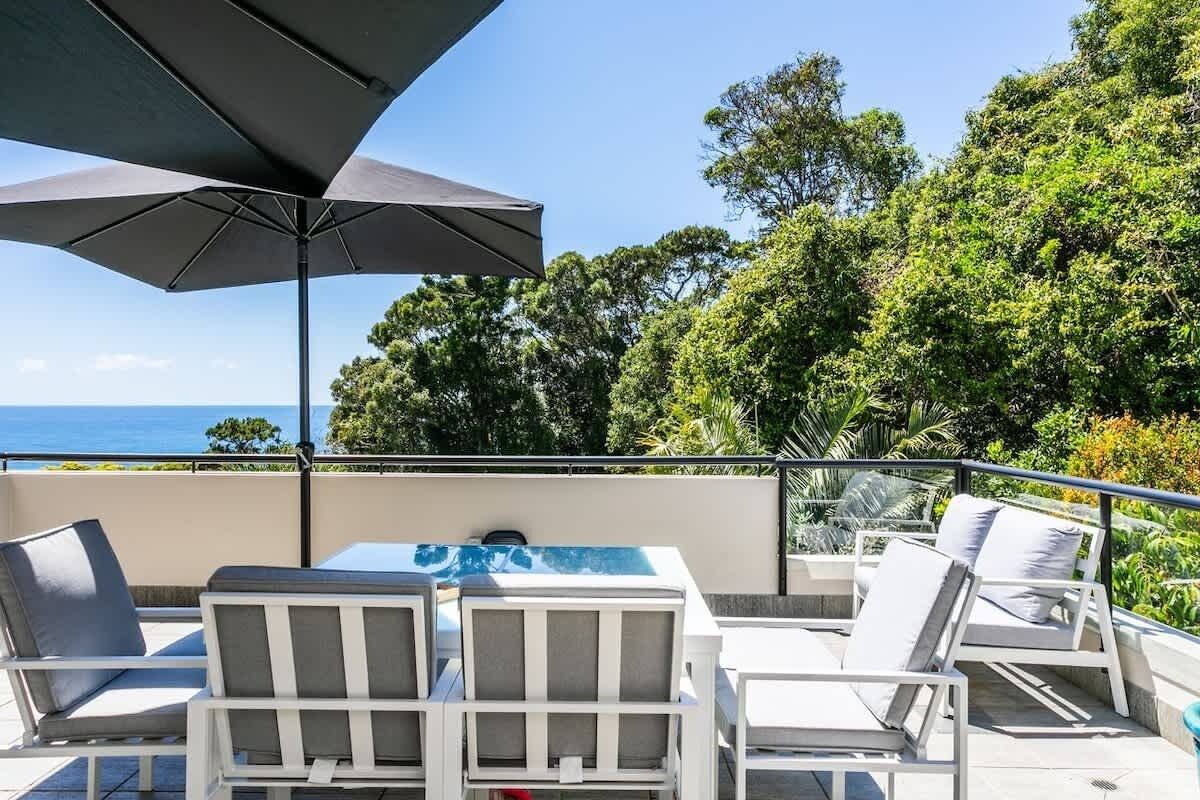 A terrace with outdoor furniture, a table, and a large umbrella.