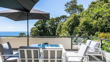 A terrace with outdoor furniture, a table, and a large umbrella.