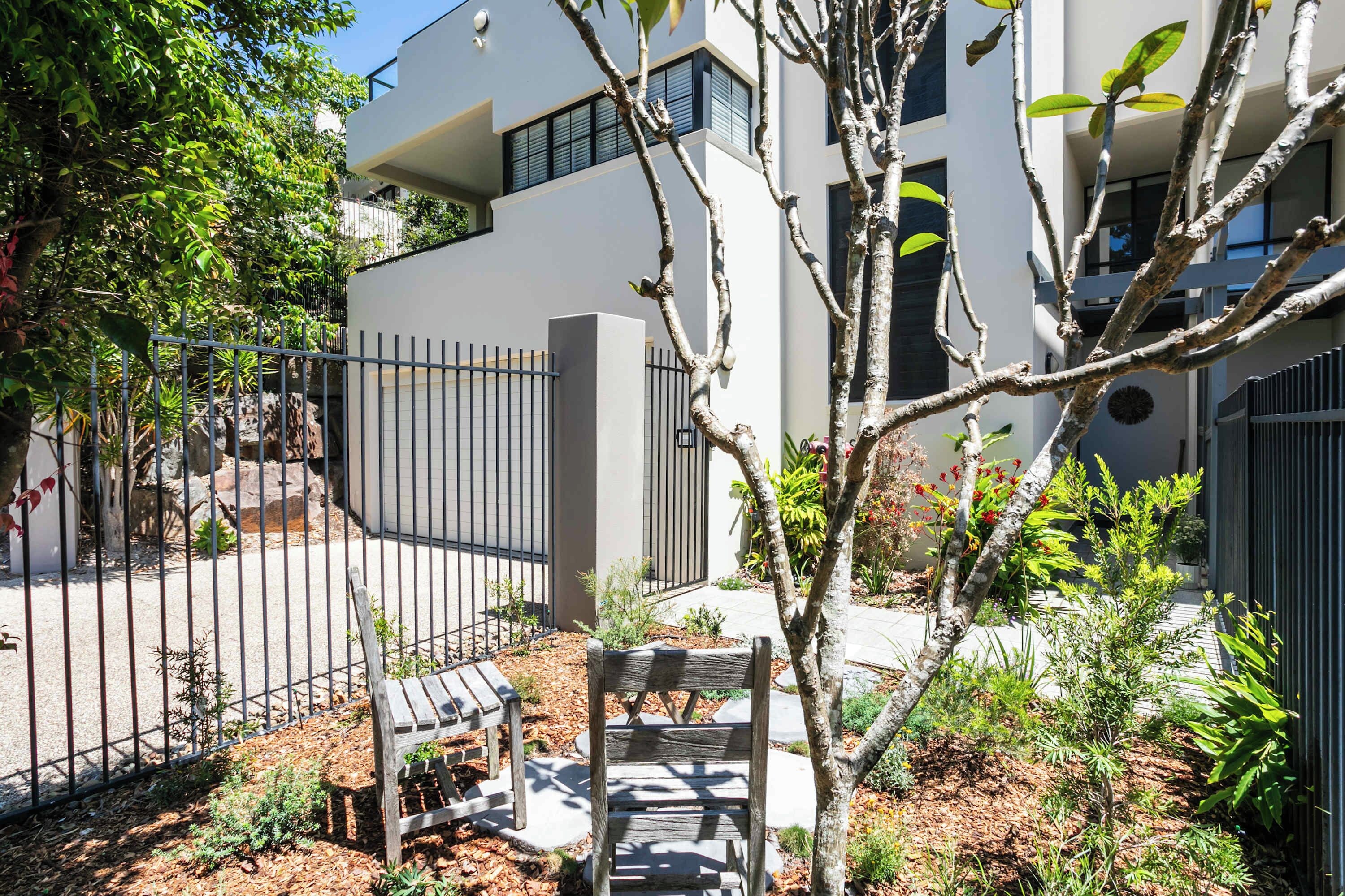 A modern building with a white facade, a metal fence, and a bench in the foreground.