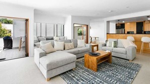 A modern living room with a grey sectional sofa, a wooden coffee table, and a patterned rug. - Ocean Outlook at Coolum (Coolum Beach)