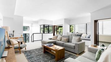 A modern living room with a sofa, coffee table, and a view of greenery outside.