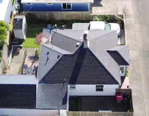 Un edificio residencial con un techo pronunciado, una chimenea visible y un patio trasero cercado.