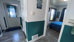 A room with a bed, a door, a vent, and a wall sign. - 🐦 Wren’s Place 2B/1Ba | Charming Seaside Retreat • Walk to Beach • Firepit (Seaside)