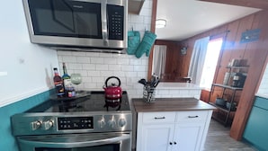 A kitchen with stainless steel appliances, a kettle, and a knife block. - 🐦 Wren’s Place 2B/1Ba | Charming Seaside Retreat • Walk to Beach • Firepit (Seaside)