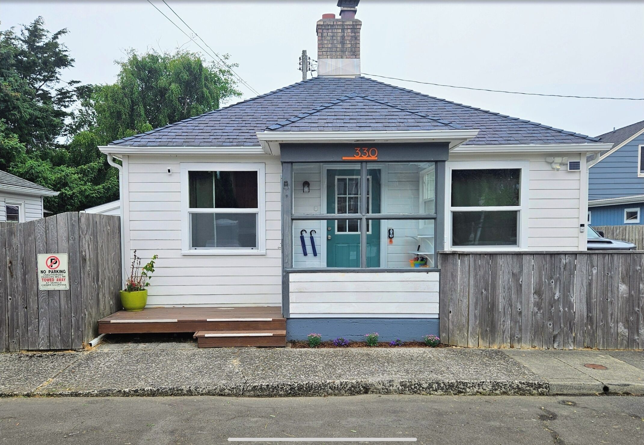 A charming coastal cottage with a welcoming teal door, wooden deck, and peaceful residential setting provides the perfect home base for your getaway.