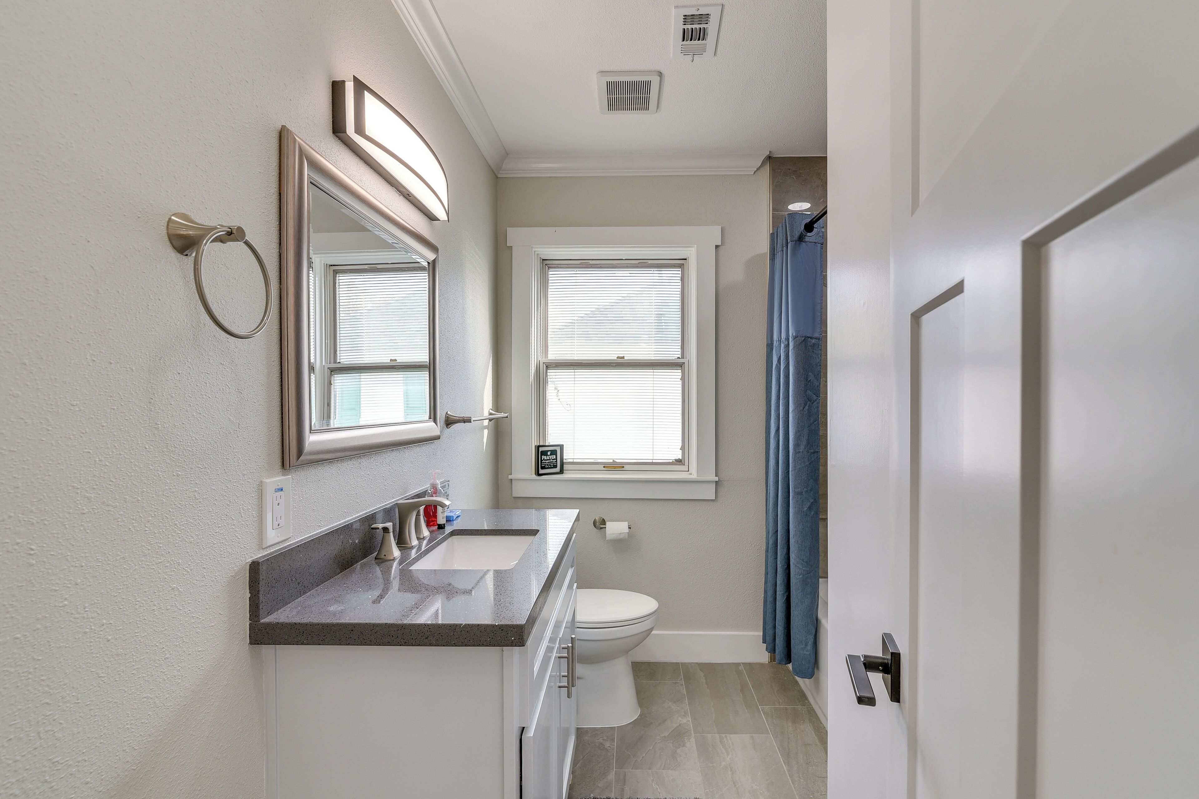 A bathroom with a sink, toilet, and window.