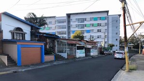 Una calle con edificios, un coche aparcado y un poste de electricidad.