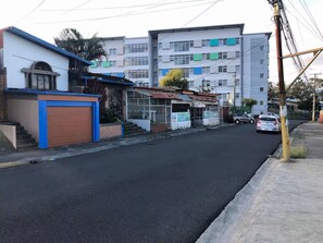 Eine Straße mit Gebäuden, einem parkenden Auto und einem Strommast.
