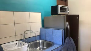 Una cocina con un lavamanos, un microondas y un refrigerador.