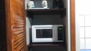 Una cocina con microondas, cafetera y un recipiente azul.