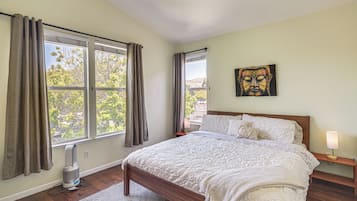 Quarto com cama, janela com cortinas, obra de arte na parede e abajur.