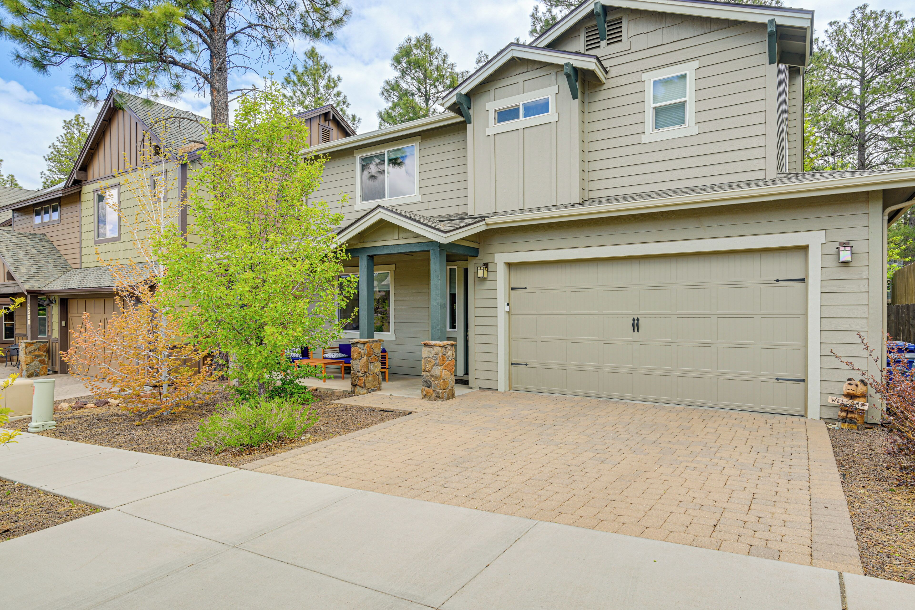 A residential house with a garage, a front porch, and a brick driveway.