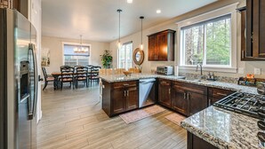Una cocina moderna con encimeras de granito, armarios de madera oscura, horno empotrado y un ventanal que proporciona luz natural.