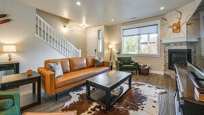 Ein Wohnzimmer mit Sofa, Couchtisch, Kamin und einer Treppe.