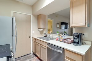 A modern kitchen with stainless steel appliances, wooden cabinets, and a white countertop. - Hike, Swim & Shop: Tucson Condo w/ Balcony (Tucson)
