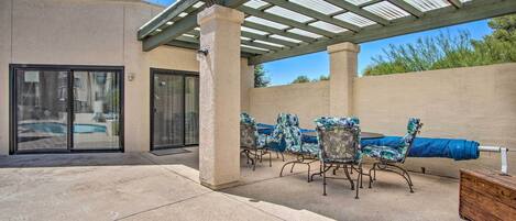 An outdoor patio with a covered seating area, a pool, and a wooden cabinet.