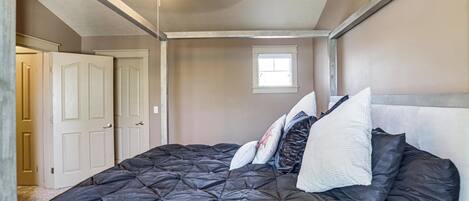 Ein Schlafzimmer mit einem großen Bett, einer Deckenleuchte, einem Fenster und einer Tür.