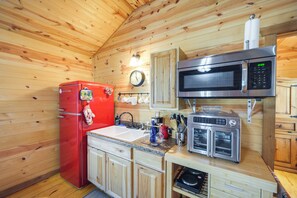 Eine kleine Küche mit Holzwänden, einem roten Kühlschrank, einer Mikrowelle und einem Spülbecken.