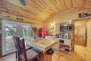 A wooden cabin interior with a dining table, chairs, a refrigerator, a microwave, and a sink. - 2 Studio Cabins! Hill Country Escape w/ Fire Pit (Johnson City)