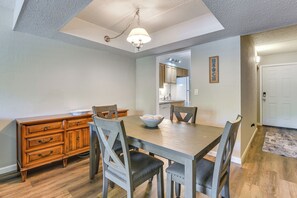 A dining area with a wooden table and chairs, a wooden cabinet, and a ceiling light fixture.