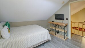 A bedroom with a bed, a small wooden table, a television, and a staircase leading to an upper level. - Lake & Dock Access! Waterfront Hot Springs Haven (Hot Springs)