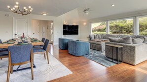 A modern living room with a dining area, a grey sofa, and a chandelier. - Dog-friendly Haven w/ Stunning Views in Bodega Bay (Bodega Bay)