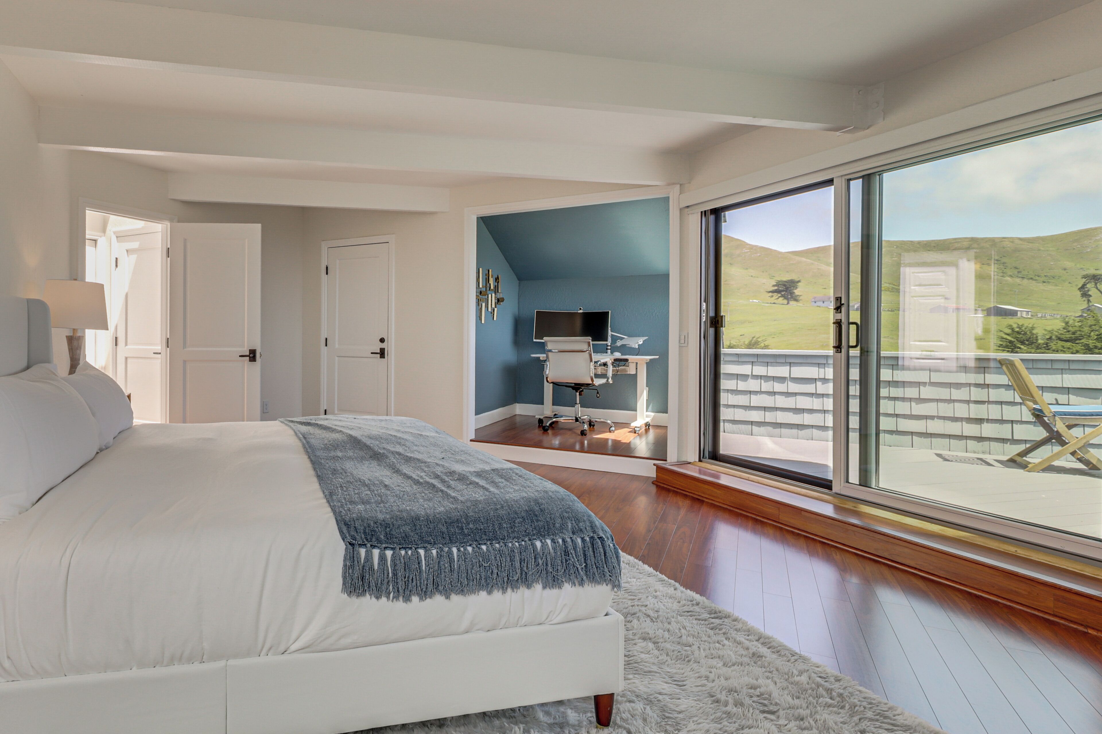 Un dormitorio con una cama grande, un escritorio con una silla, un televisor y vistas al exterior.