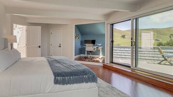 Un dormitorio con una cama grande, un escritorio con una silla, un televisor y vistas al exterior.