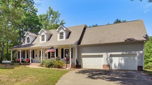 Une maison à deux étages avec un garage, une véranda et une pelouse bien entretenue.